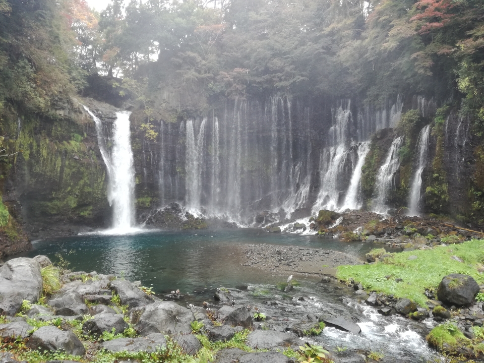 Series of cascading waterfalls in a lush green setting.