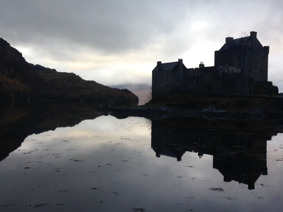 Silhouette of a castle with water reflection at sunset.