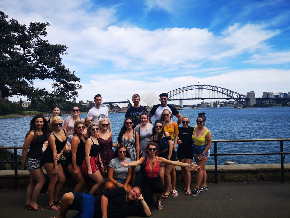 A group of people posing with the Sydney Harbour Bridge in the background.