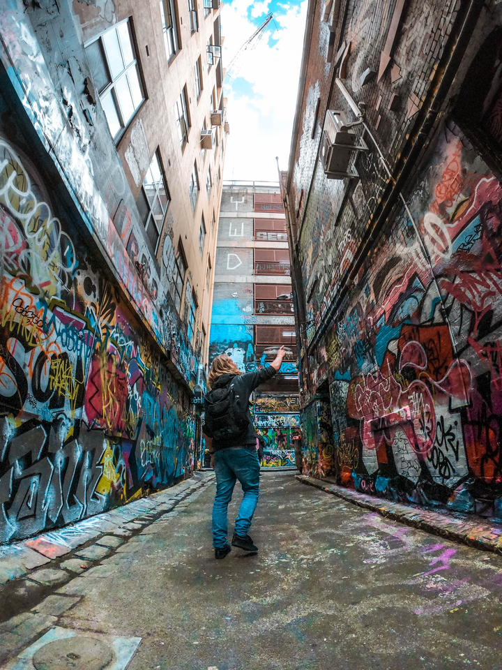Colorful graffiti in an alleyway with a person observing.