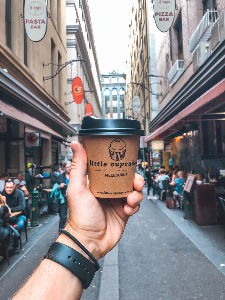A hand holding a coffee cup from a Melbourne cafe.