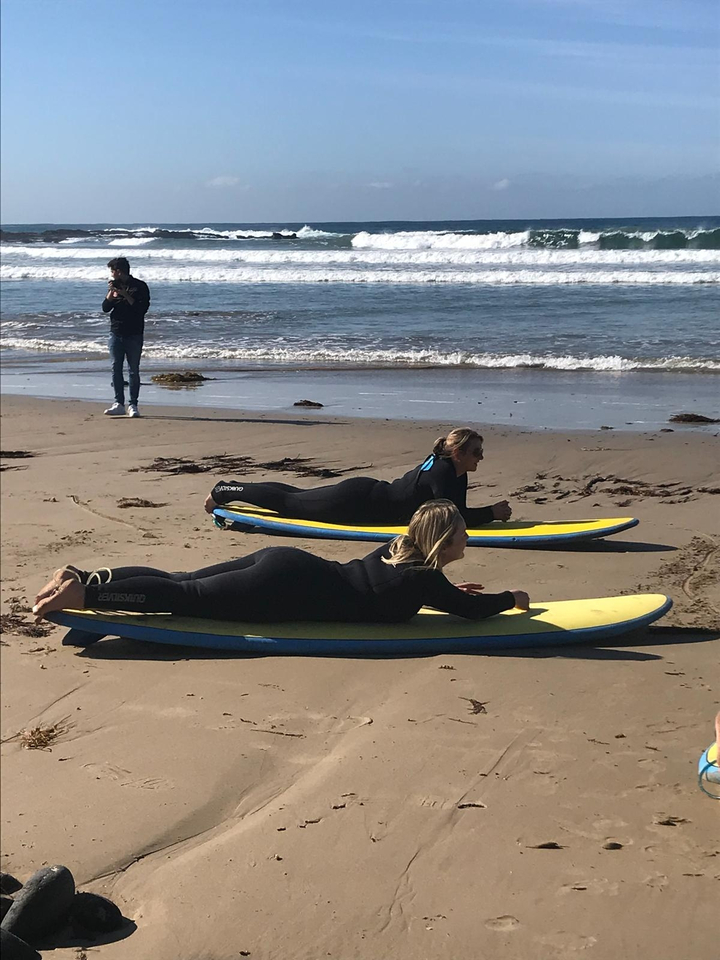 Surfers practicing on the beach with surfboards.