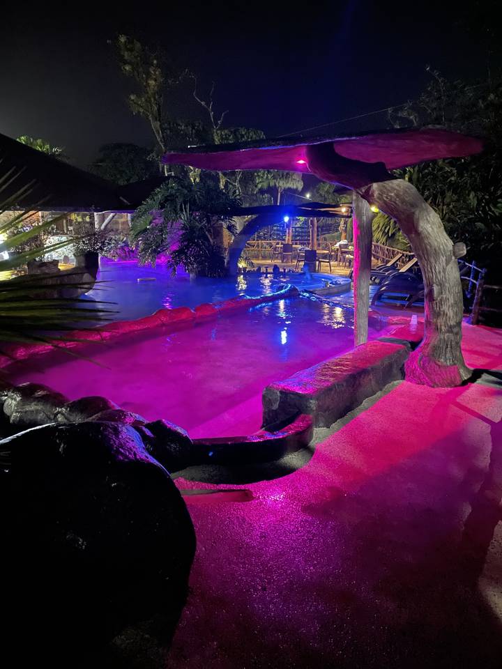 Colorful lights illuminating a pool area at night.