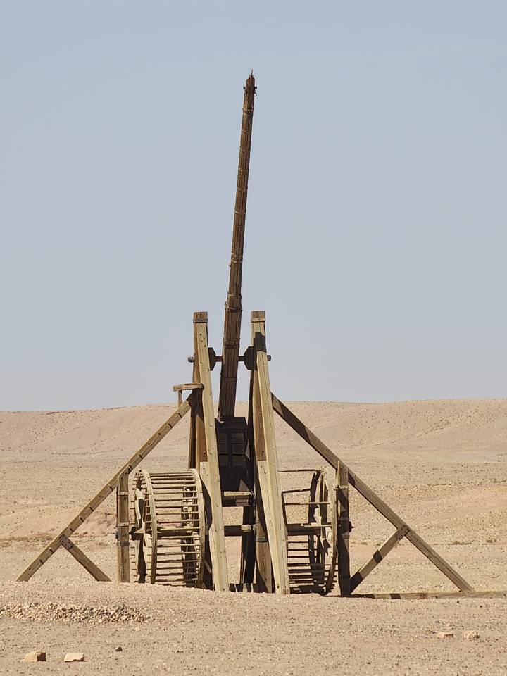 An old catapult or trebuchet in a desert setting.