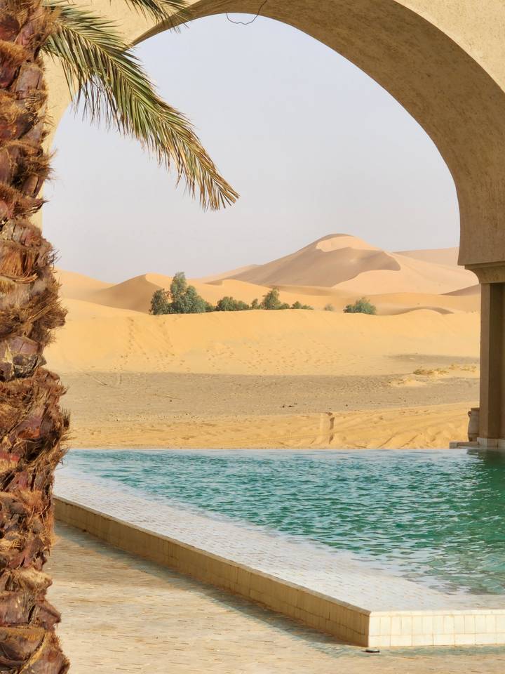 Desert with a tiled path or pool leading into dunes.
