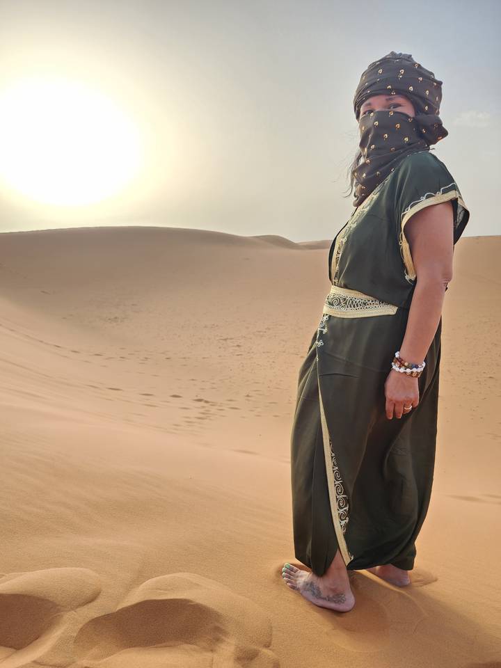 Person in the desert with a sand dune background.