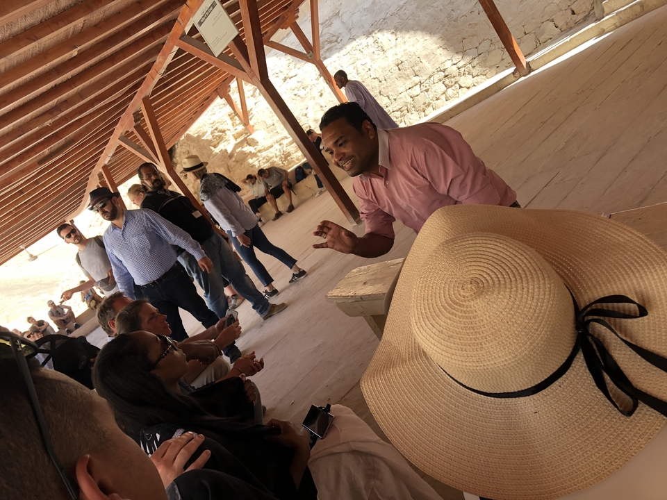 Des gens écoutent un guide dans une zone ombragée.