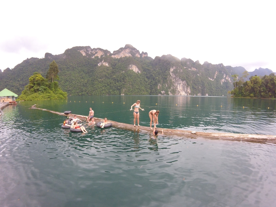 People relaxing and playing in a lake with scenic mountains.
