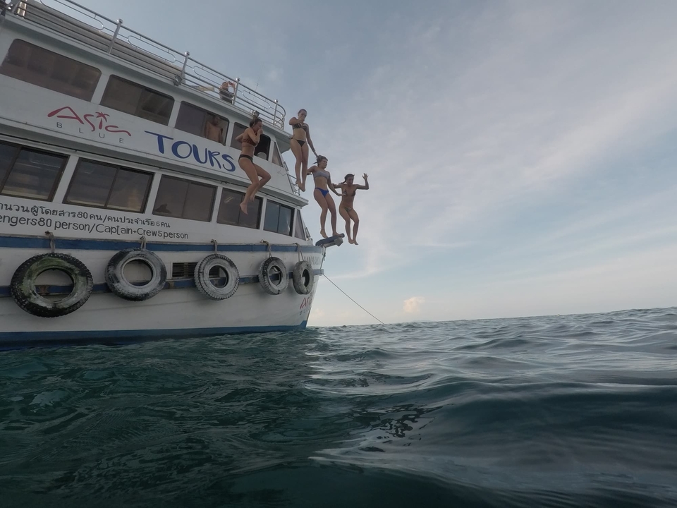 People jumping off a boat into the ocean.