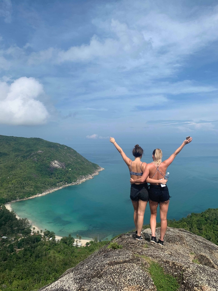 Two people embracing with an ocean and hillside view.