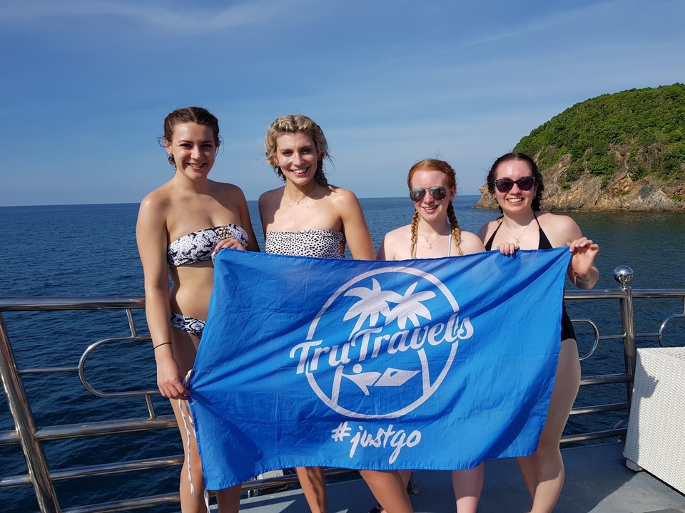 People holding a travel banner with the ocean in the background.