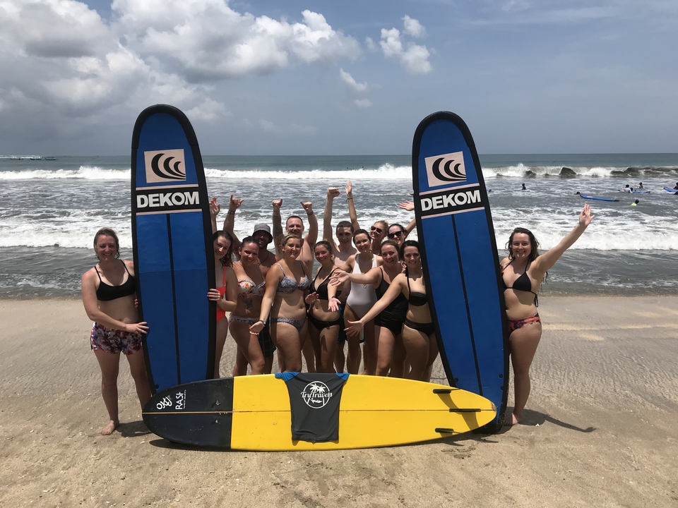 Group of surfers posing with surfboards on the beach.