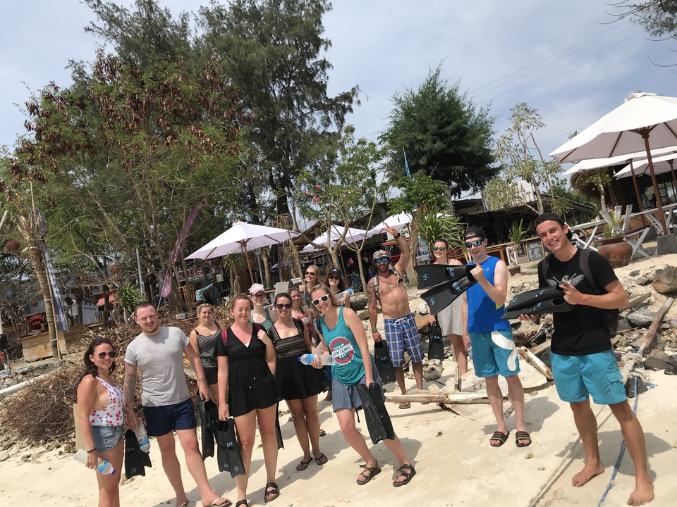 Group of people with snorkeling gear on a sandy beach.