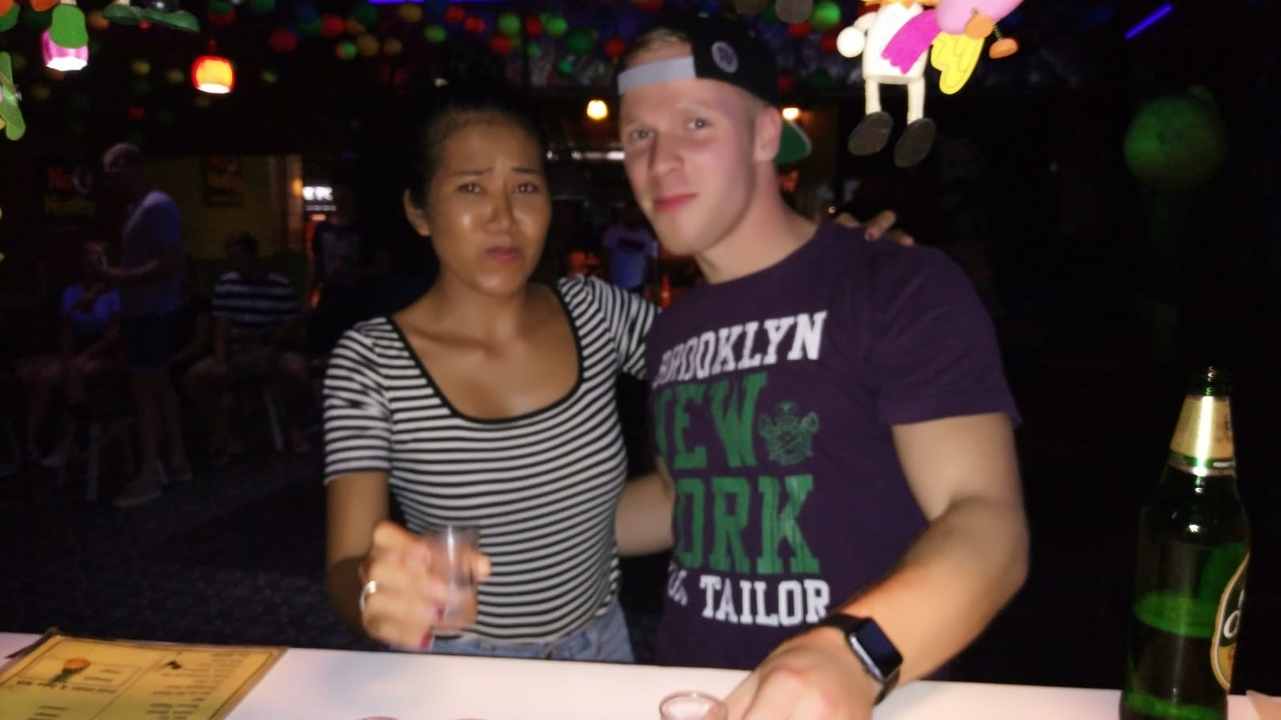 Two people at a bar with colorful lights.