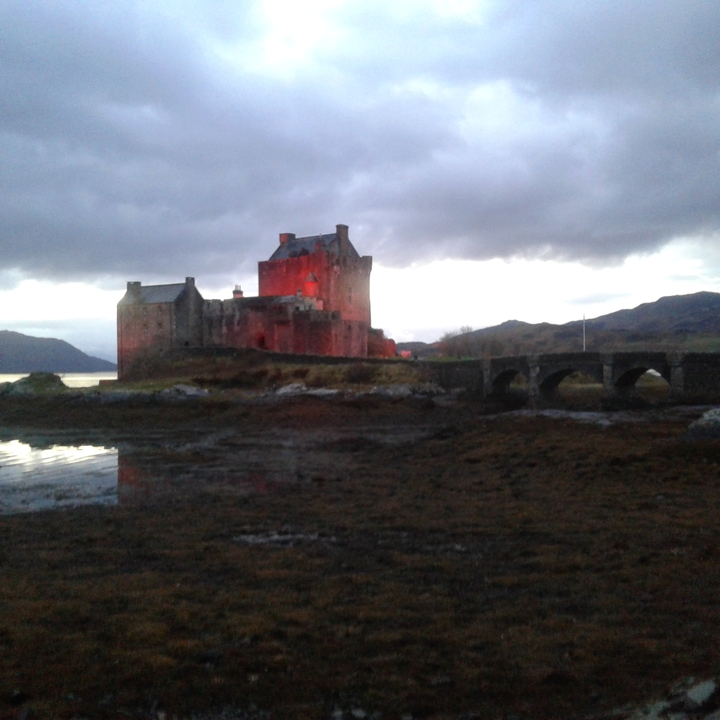 Château historique avec un pont au premier plan au crépuscule.