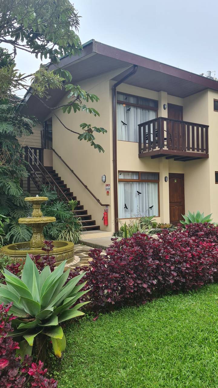 Building with lush garden and red foliage.
