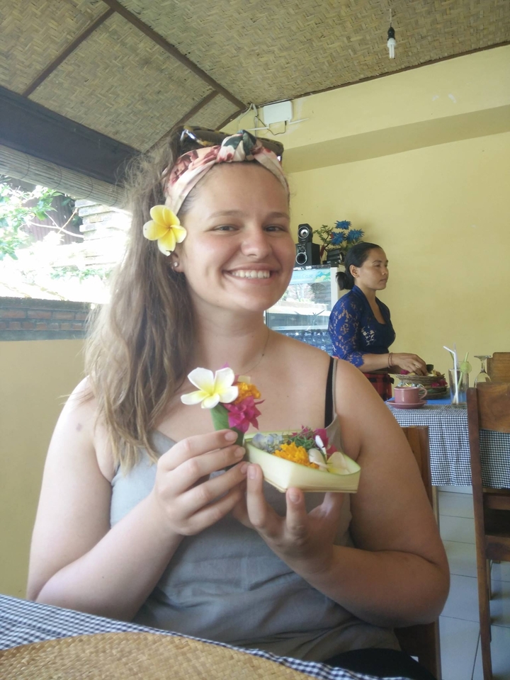Smiling woman holding a decorative flower arrangement.