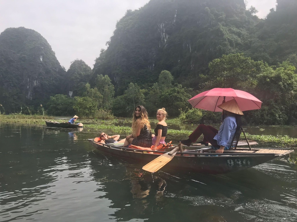 Tourists being rowed along a river surrounded by lush green mountains.