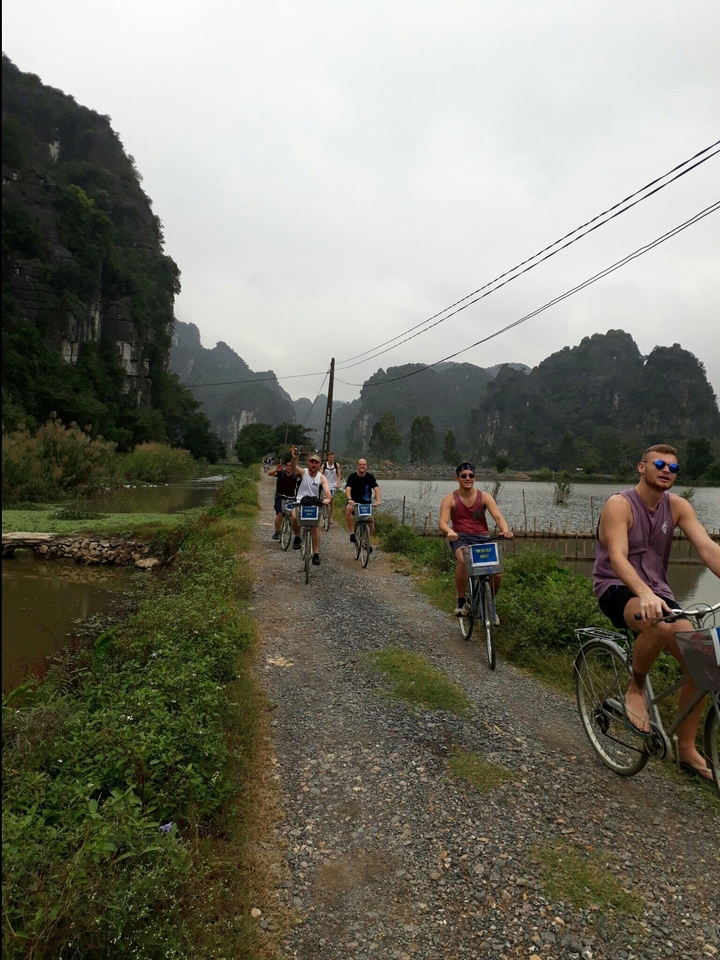 Group of young people cycling along a rural path with scenic hills.