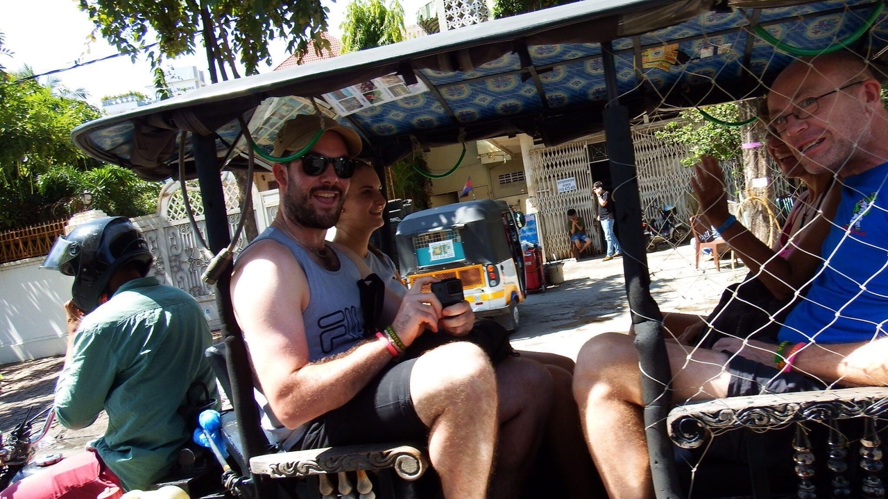 People inside a tuk-tuk on a city street.