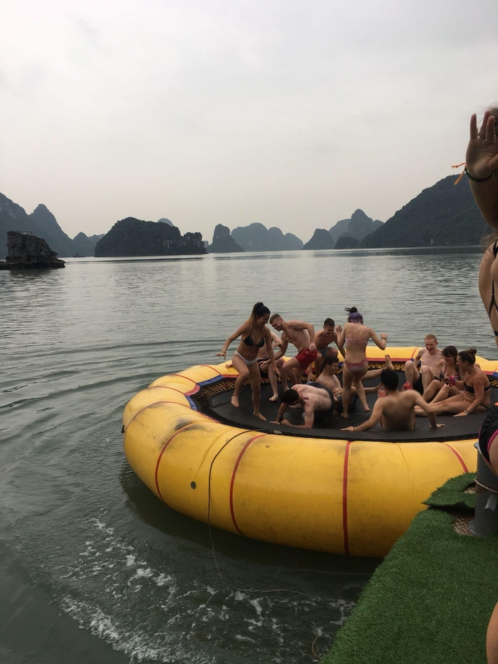 Group of people enjoying a trampoline float in the water with scenic rocks.