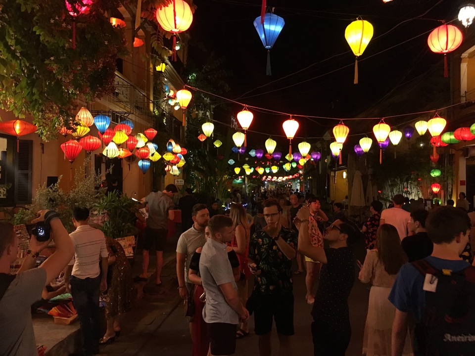 Bustling street at night with colorful illuminated lanterns and people walking.