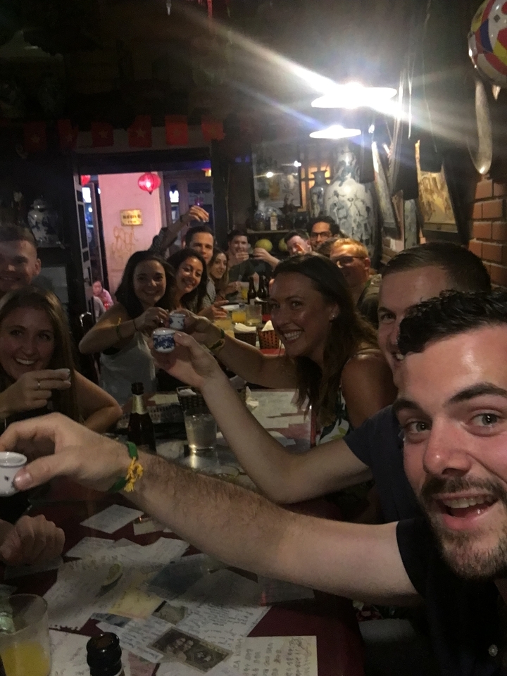 Group of people raising glasses in a bar setting.