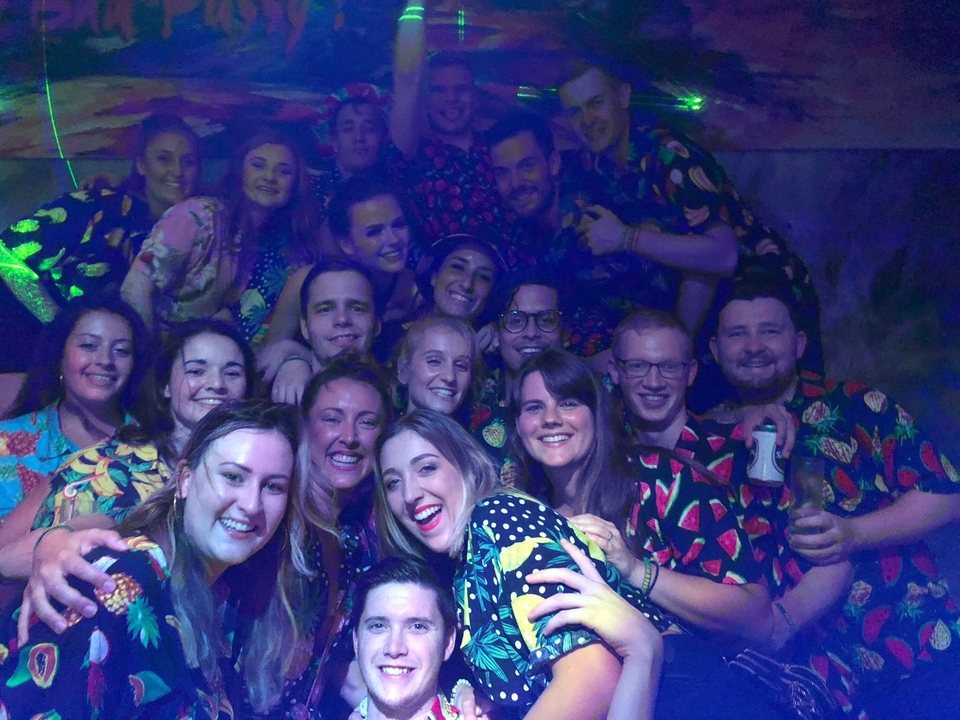 Large group of people in a club setting wearing tropical-themed outfits.