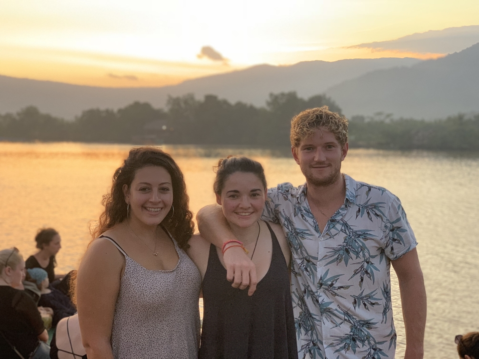 Friends posing by a river at sunset.