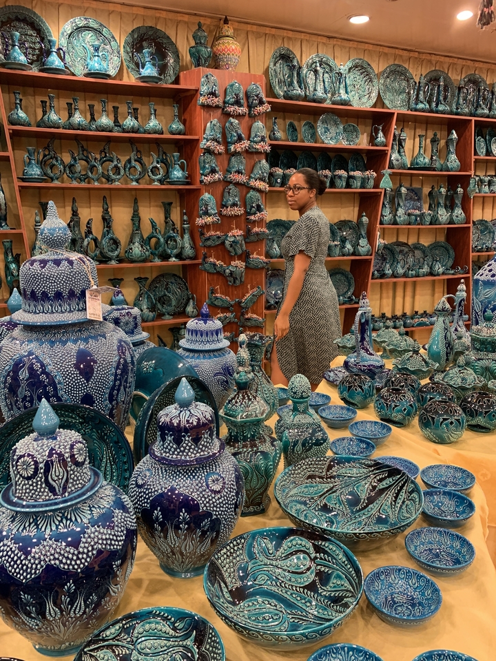 A person exploring a shop full of vibrant Turkish ceramics.
