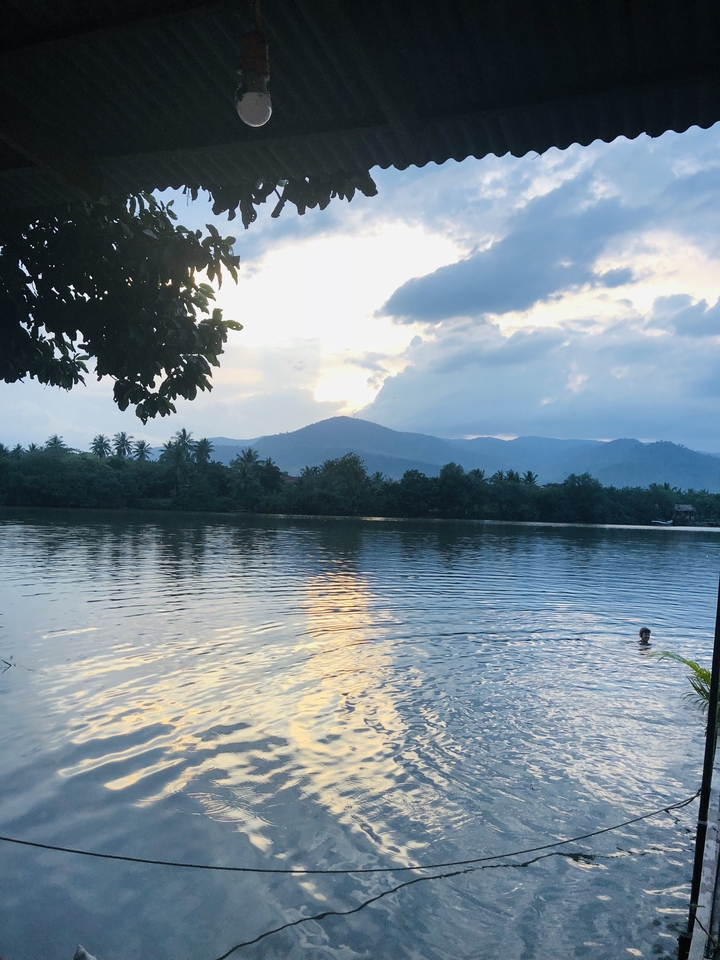 A serene view of a swimmer in a river with mountains in the background.