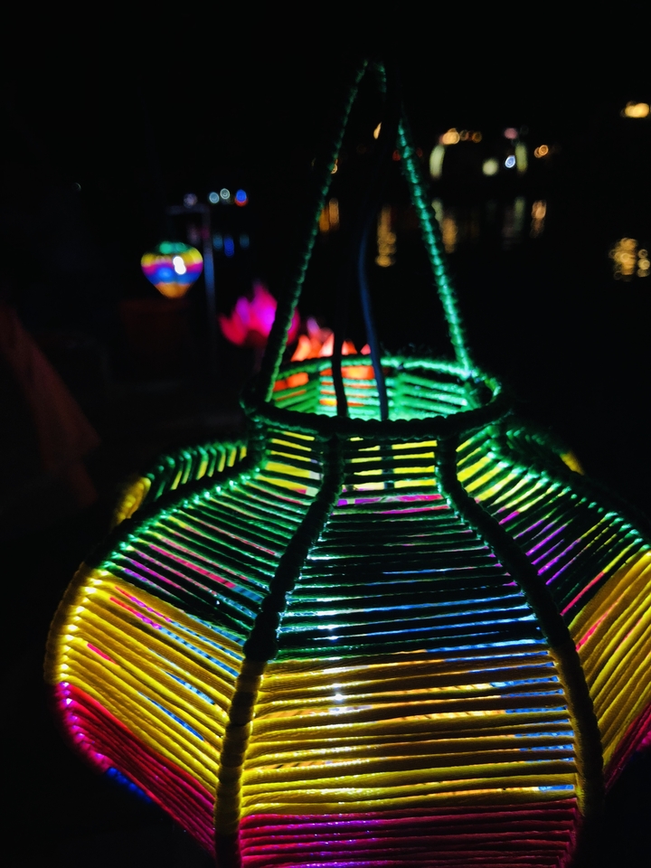 A close up of a colorful woven lantern in the dark.