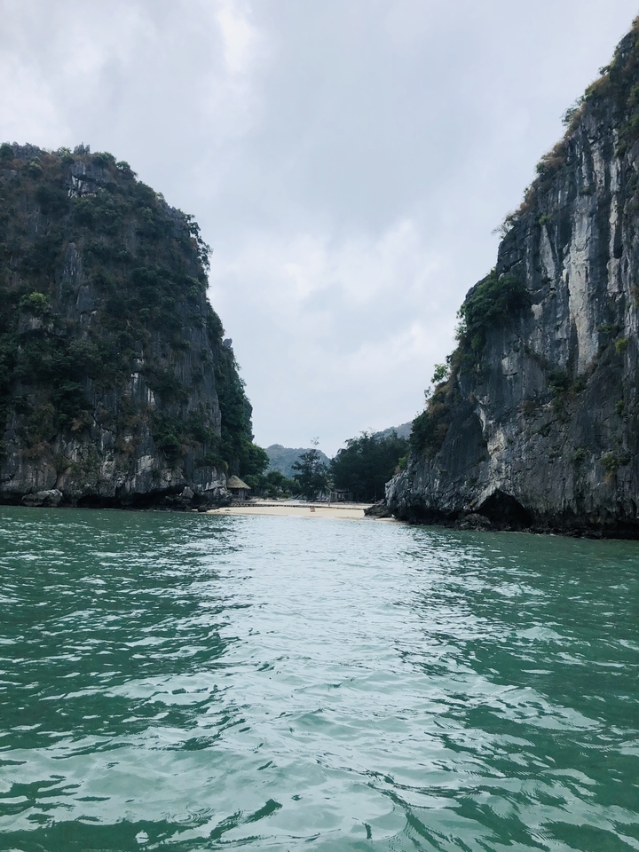 A secluded beach surrounded by towering rocky cliffs.