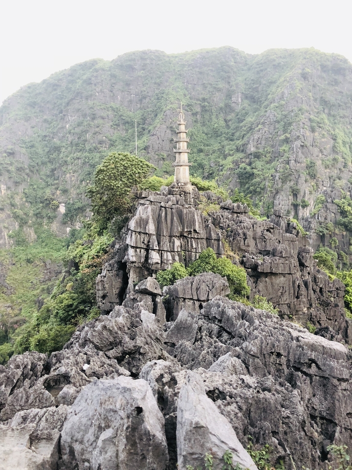 A stone pagoda on top of a rocky hill surrounded by lush greenery.