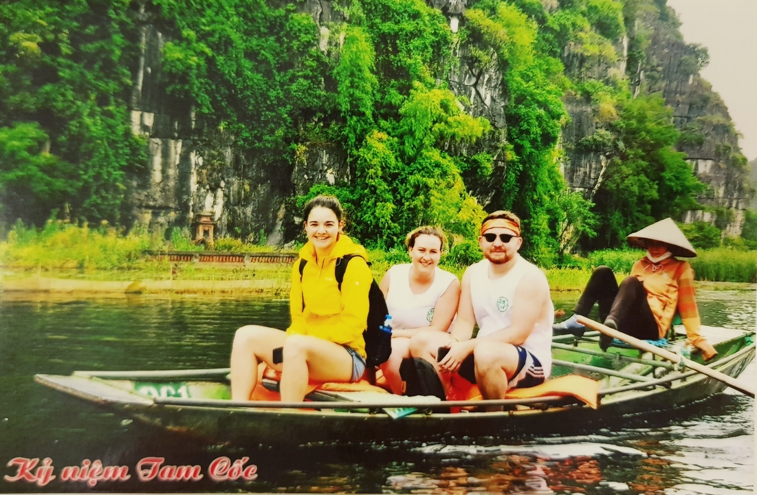People in a small boat rowing on a river surrounded by cliffs.