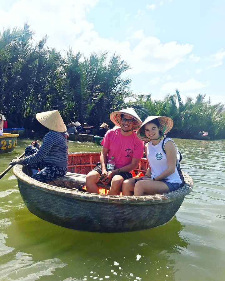People wearing traditional Vietnamese hats in a circular boat.
