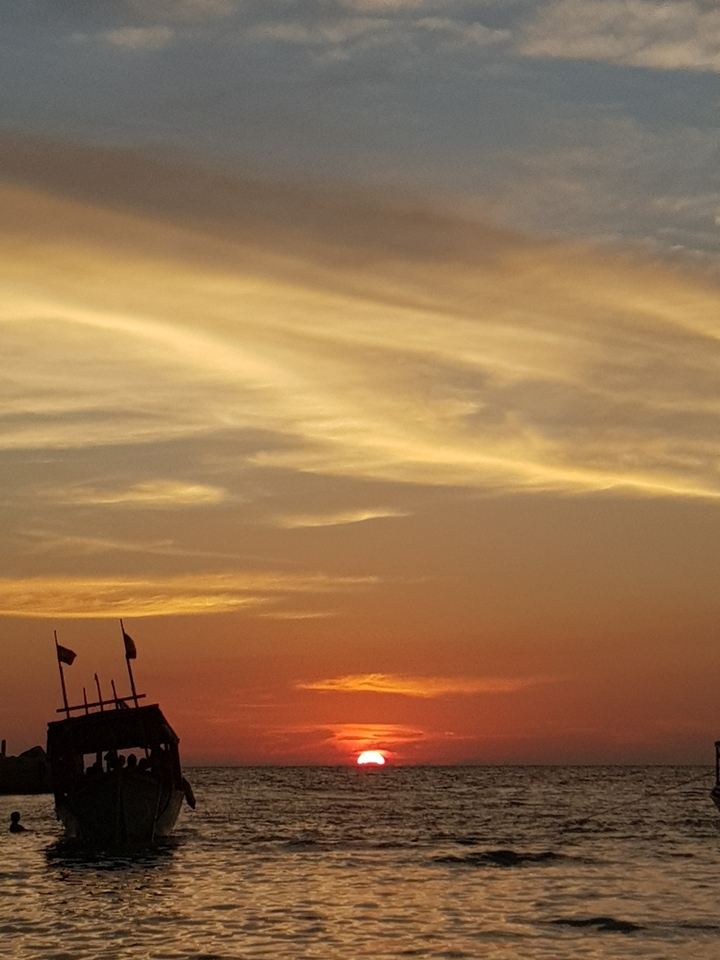A sunset with soft clouds and silhouetted flags.