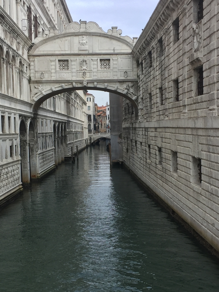 A canal in Venice with bridges and historic buildings lined along.