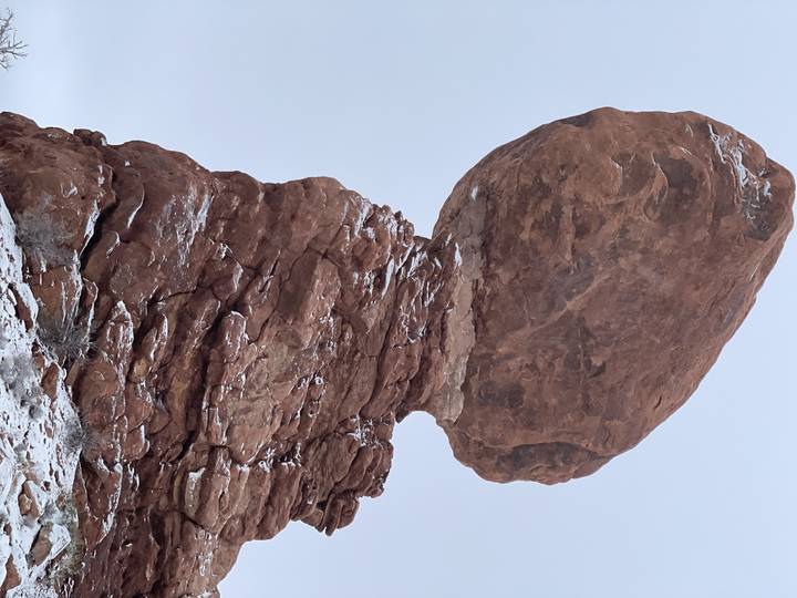 Balancing rock formation against a snowy background.