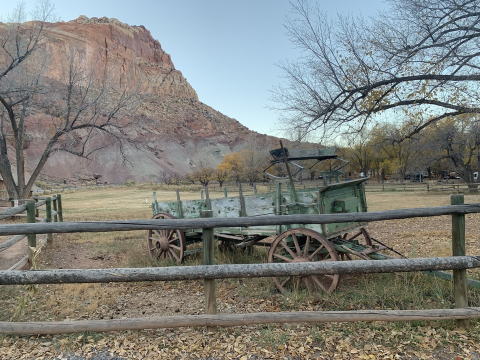 Historic wagon in a fenced area with mountains.