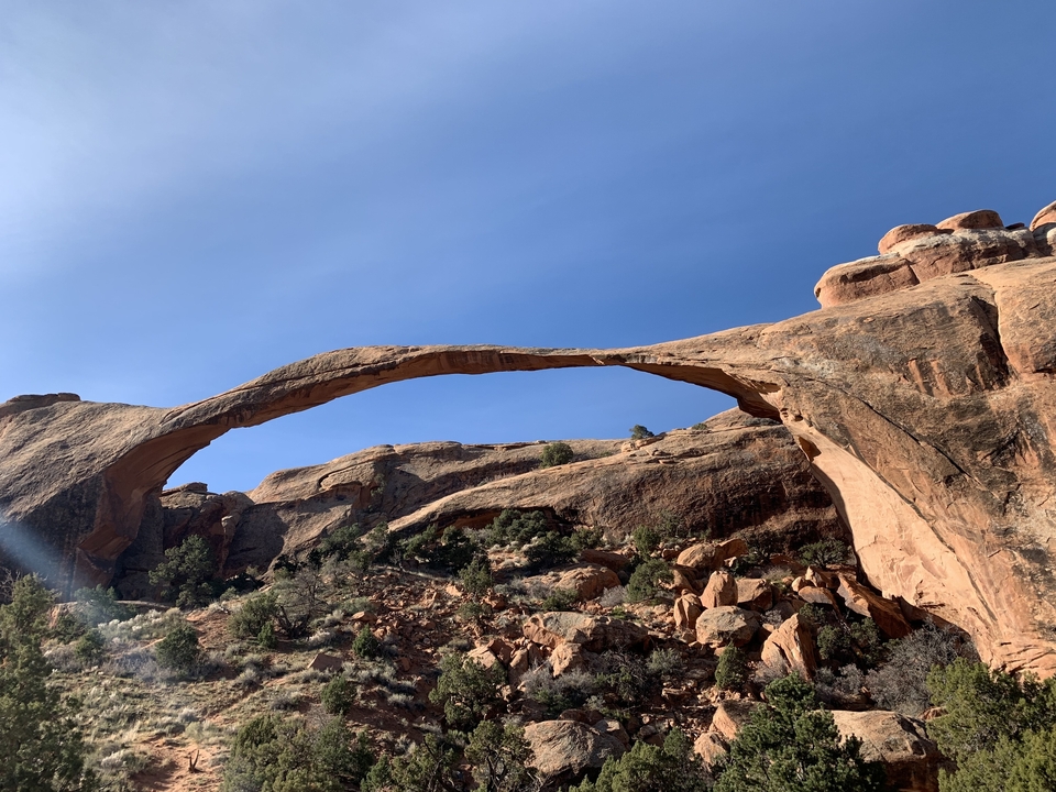 Large natural arch in a rocky landscape.