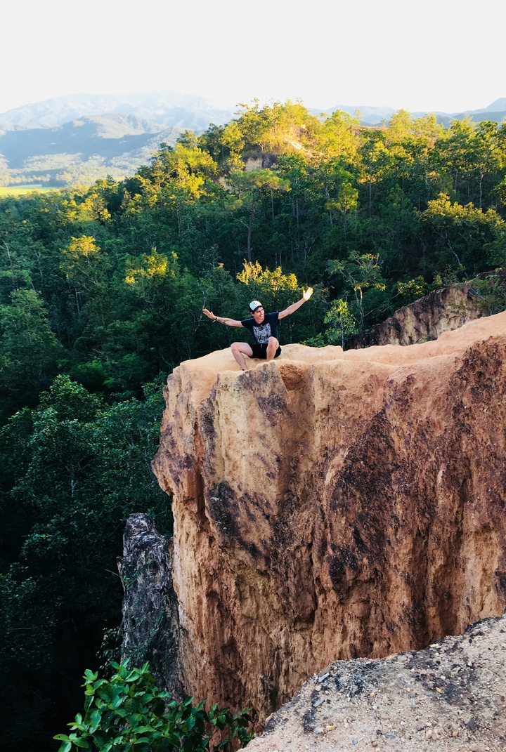 A person posed triumphantly on a rocky ledge.