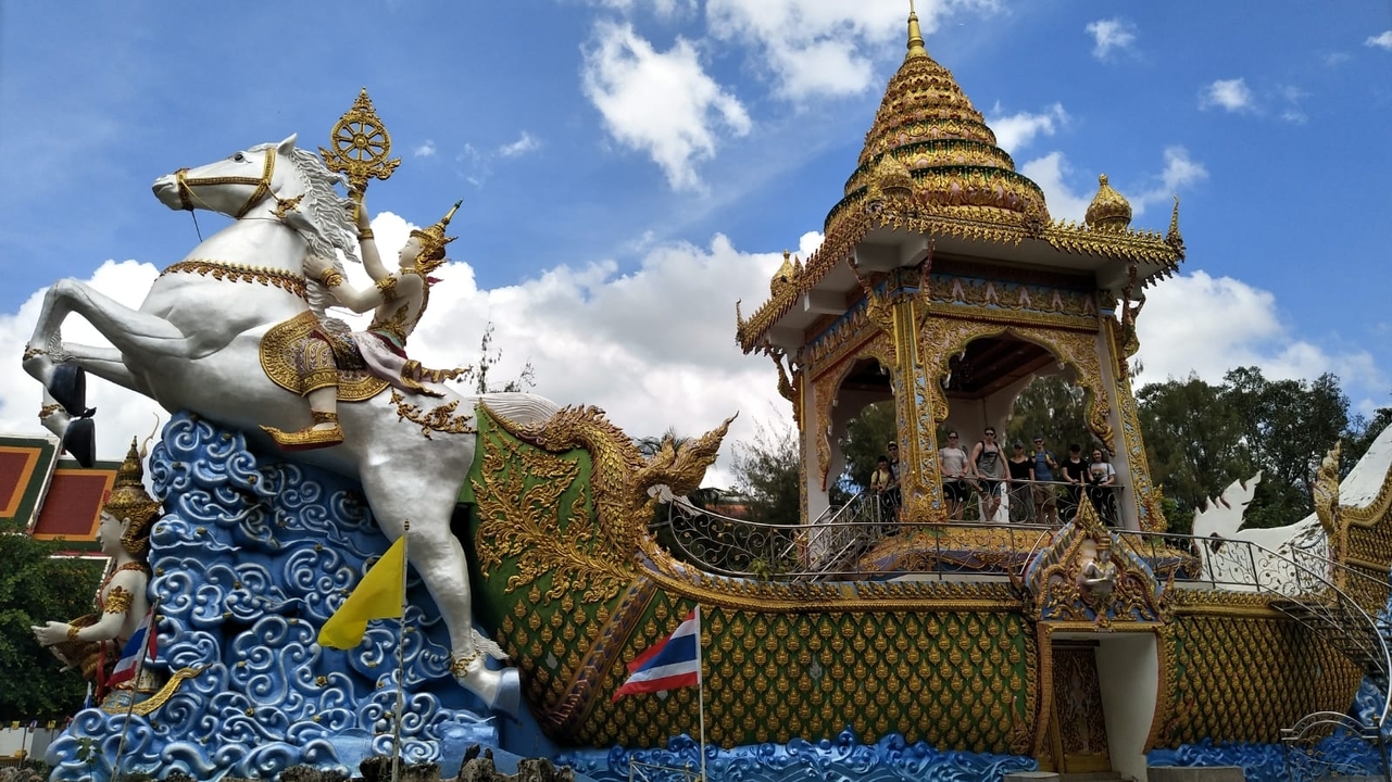 Ornate temple structure with a horse statue against a blue sky.