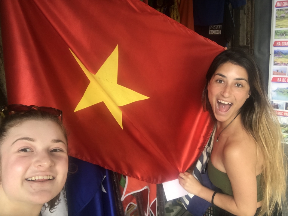 Two women smiling and holding a Vietnamese flag.