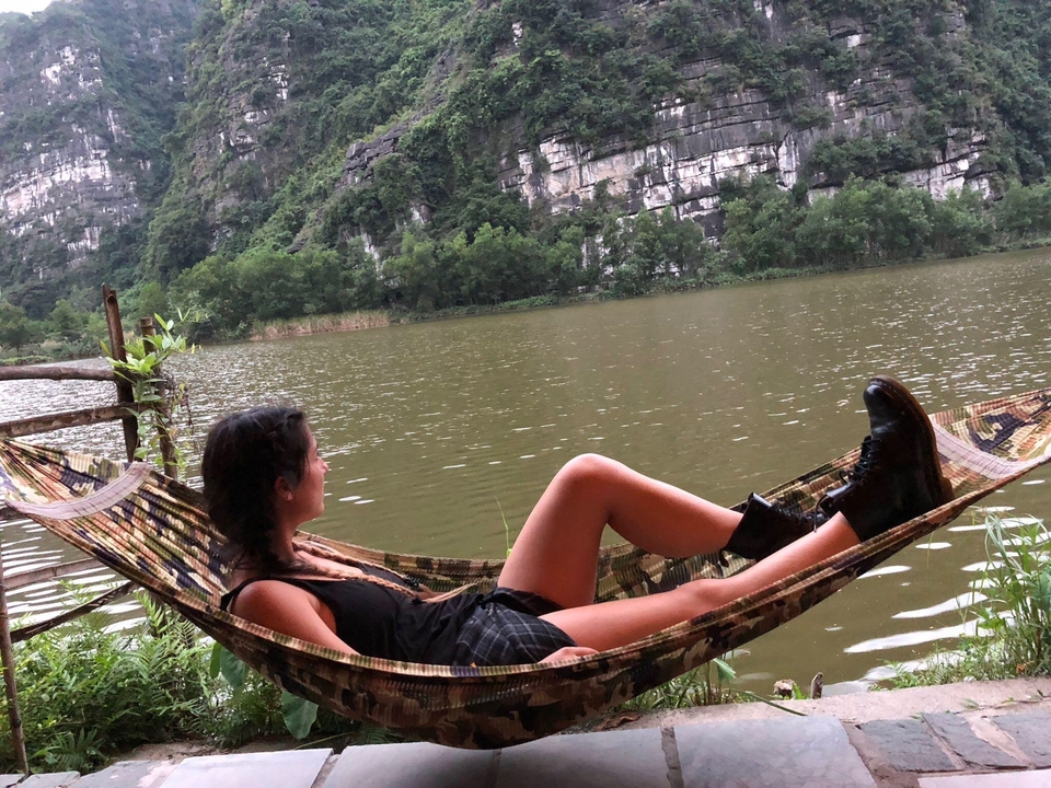 Woman relaxing on a hammock near a lake.