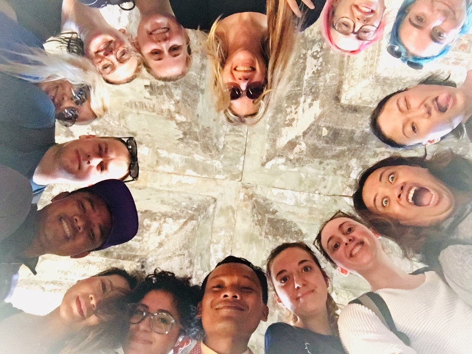 Groupe de personnes regardant vers le haut, formant un cercle sous un toit de pierre.