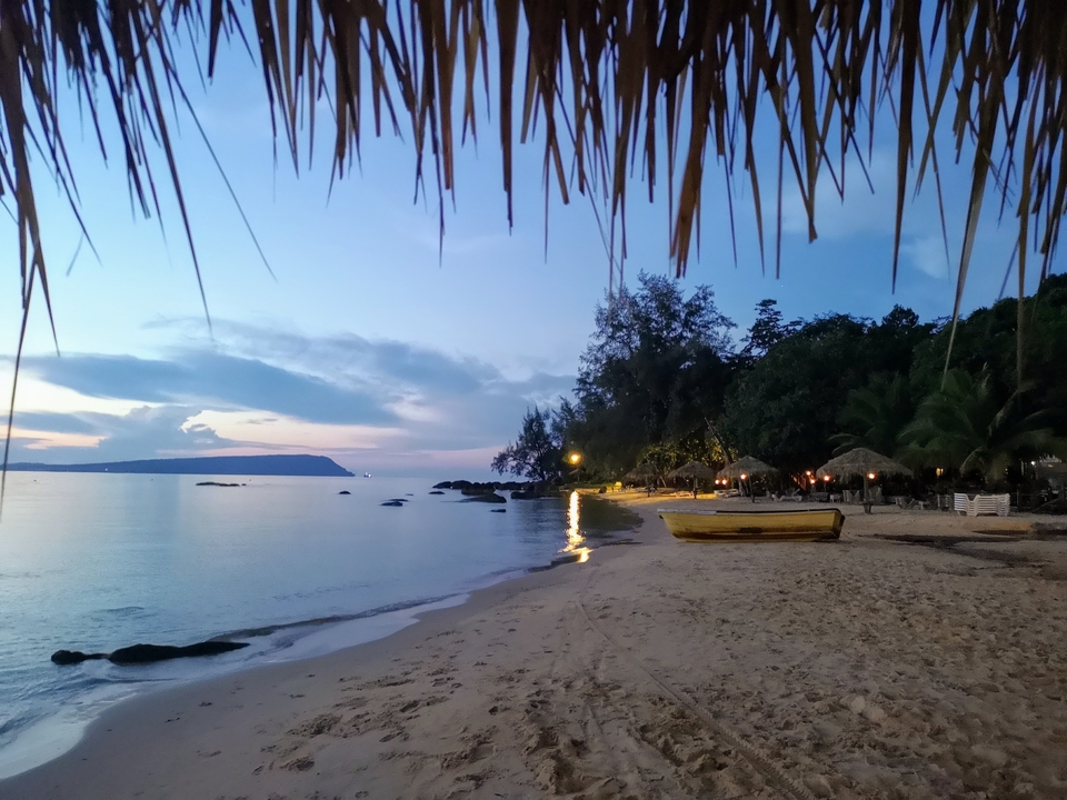 Beach scene during sunset with a boat docked on the sand.