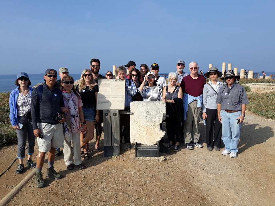 Groupe de personnes posant sur un site archéologique près de la mer.