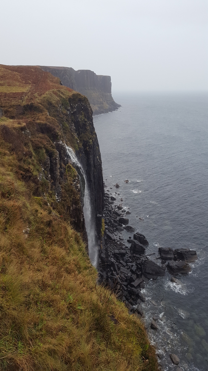 Waterfall plunging into rocks by the sea.