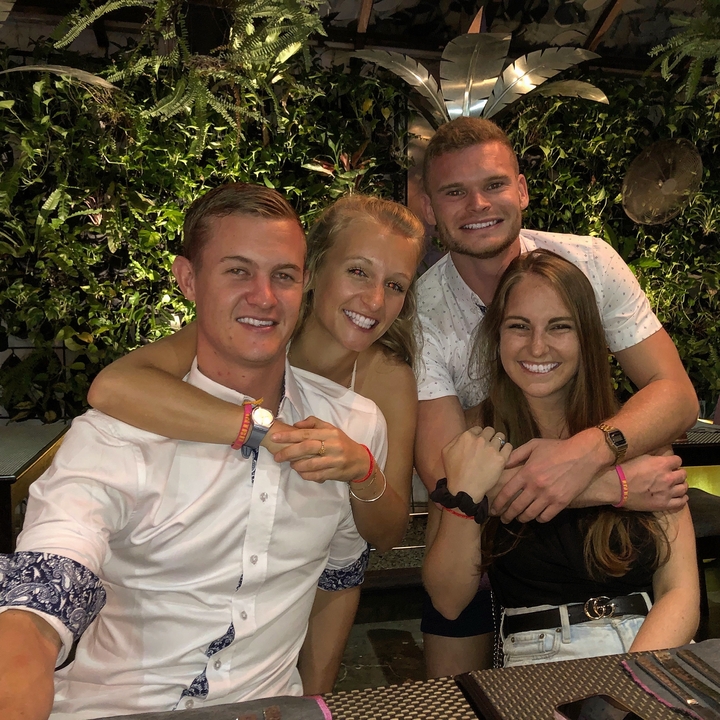 Four people posing with a green wall backdrop.